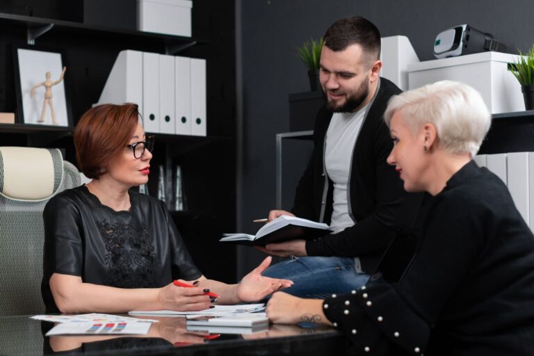 Tres personas hablando en un despacho con documentación en la mano