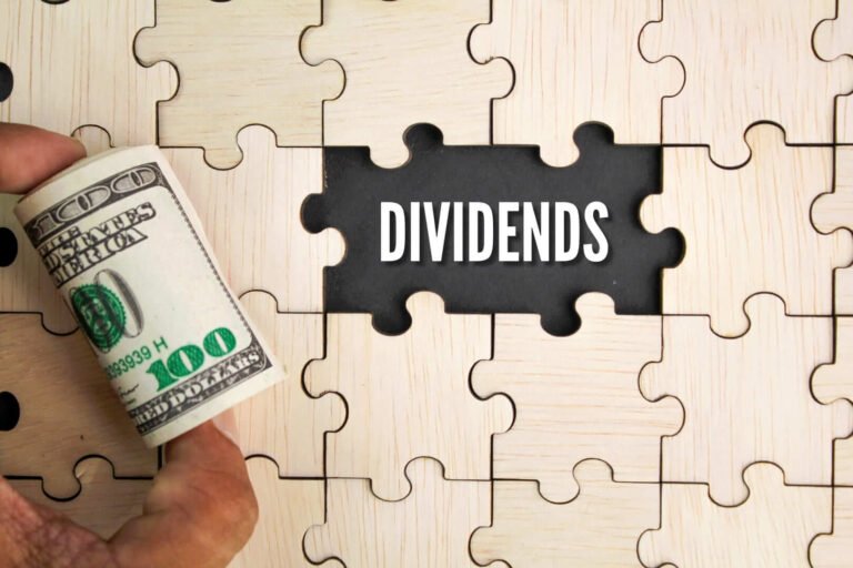 una mano con un fajo de billetes y la palabra dividendos en inglés