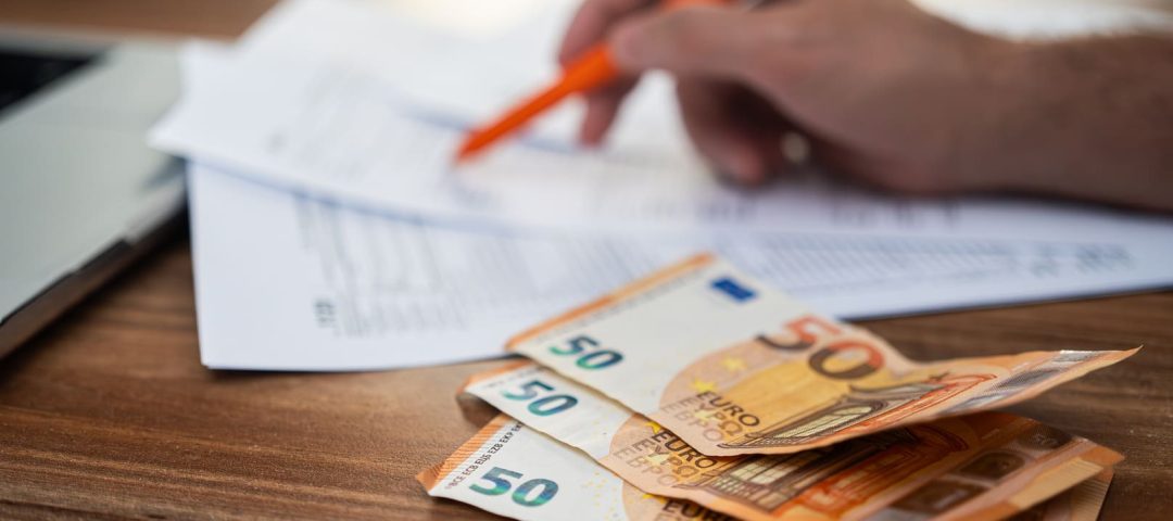 Una mano haciendo cuentas para amortizar hipoteca junto a unos billetes de 50 euros