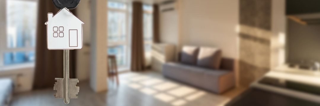 Las llaves de una vivienda sobre un fondo desenfocado que muestra la vivienda