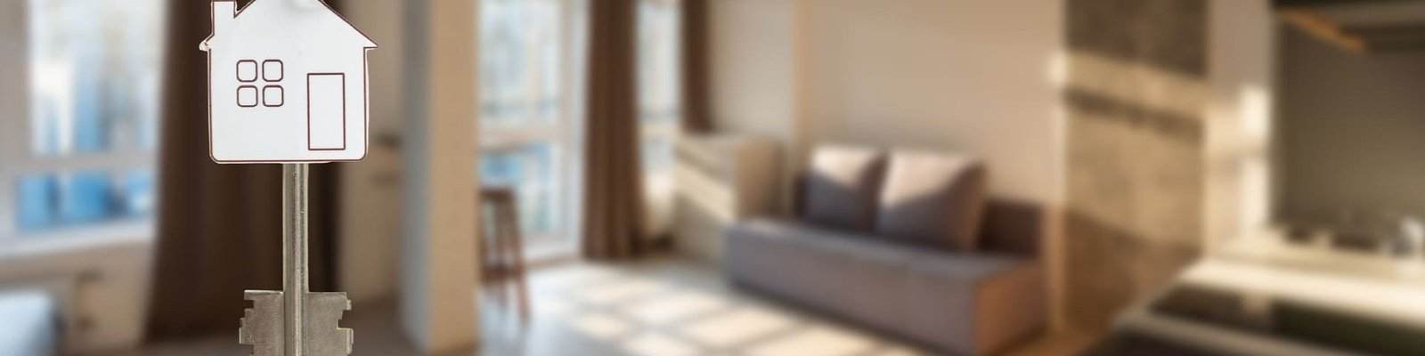 Las llaves de una vivienda sobre un fondo desenfocado que muestra la vivienda