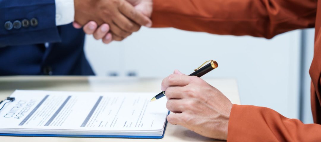 Dos persona dándose la mano sobre un documento