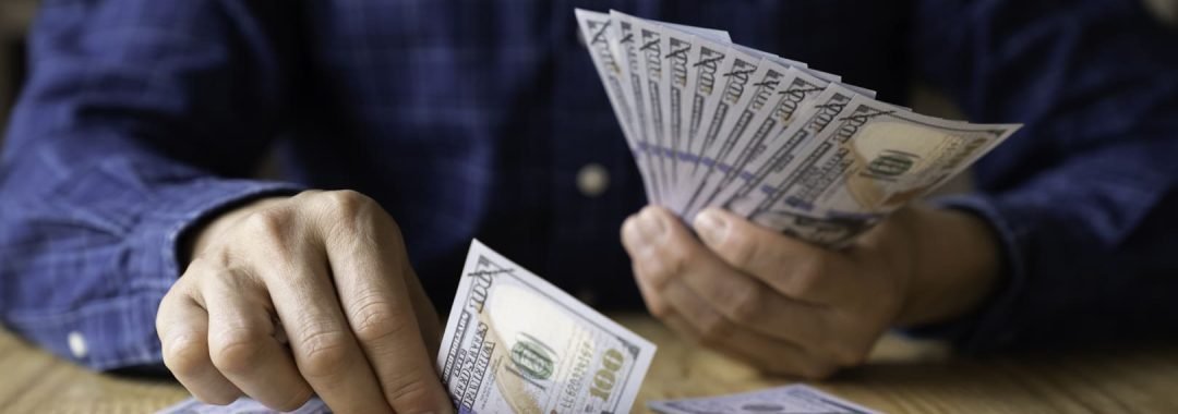 Un hombre organizando billetes en diferentes montones