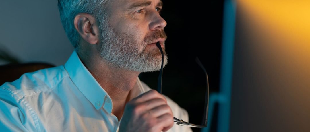 Un hombre pensativo mirando la pantalla del ordenador