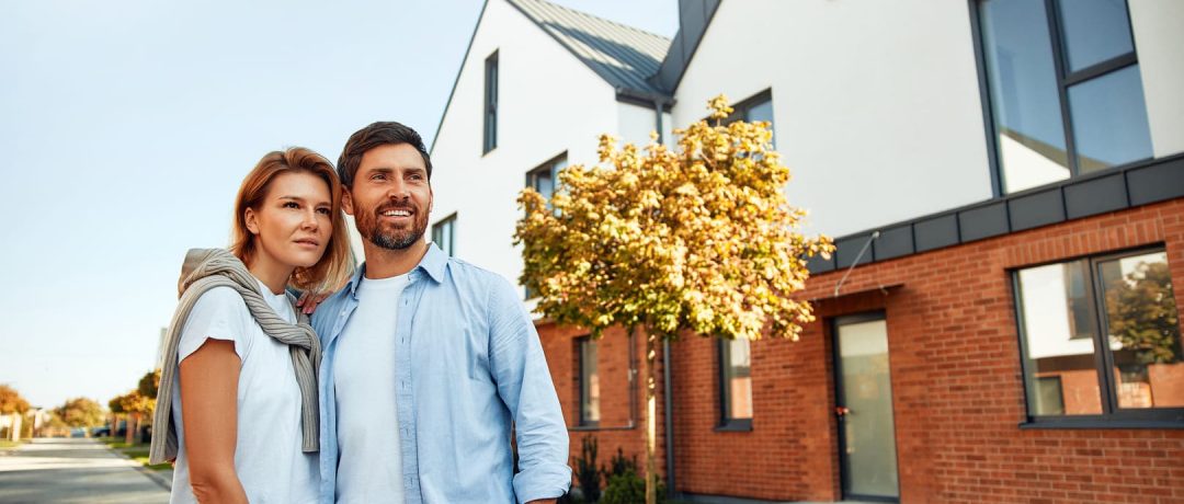 Una pareja feliz delante de su vivienda ya construida