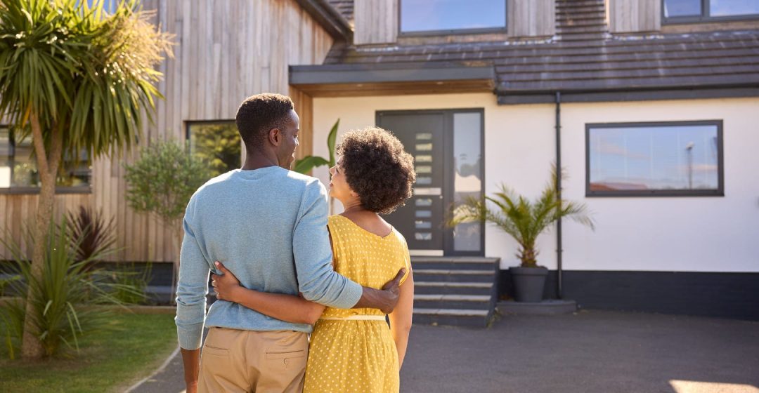 Una pareja sonriente delante de su casa