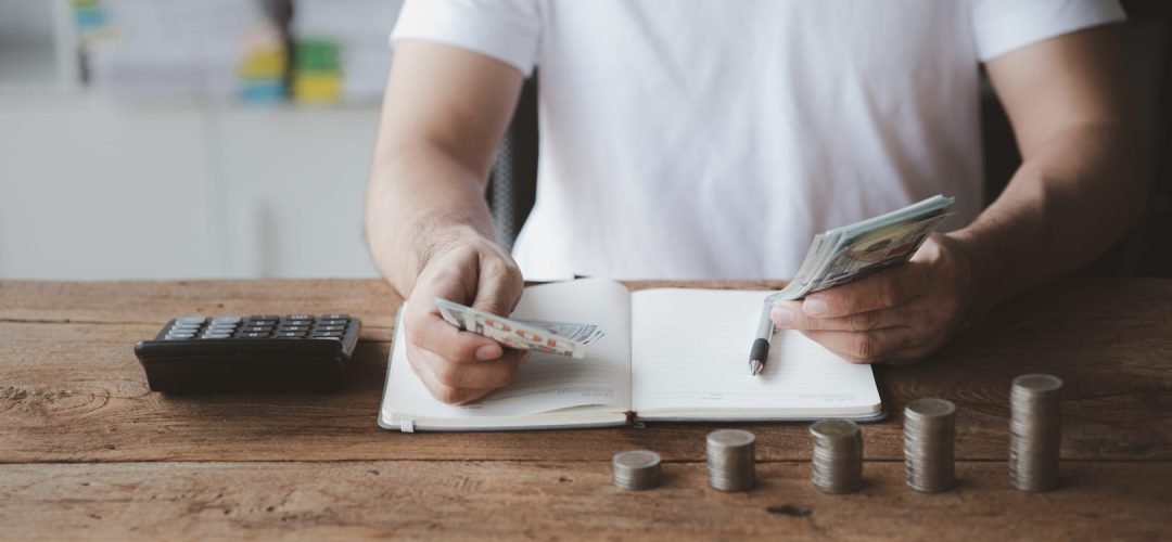 un hombre haciendo cálculos con una calculadora y dinero sobre la mesa