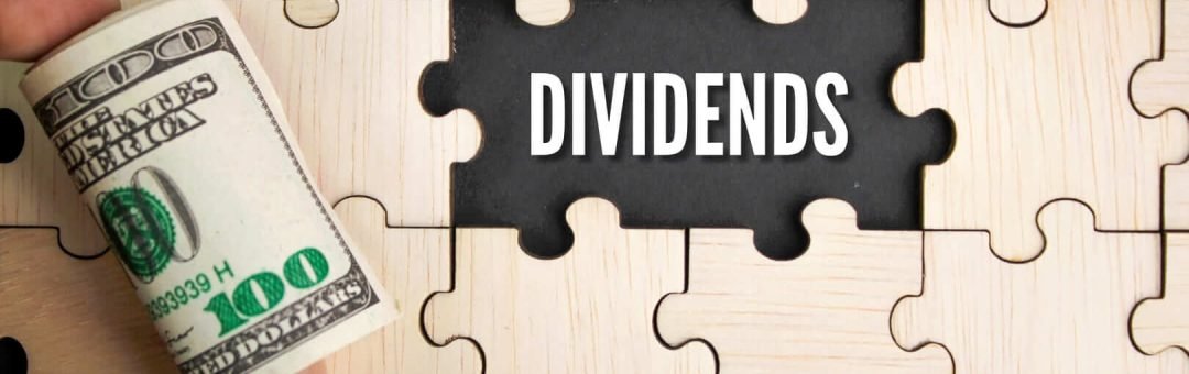 una mano con un fajo de billetes y la palabra dividendos en inglés