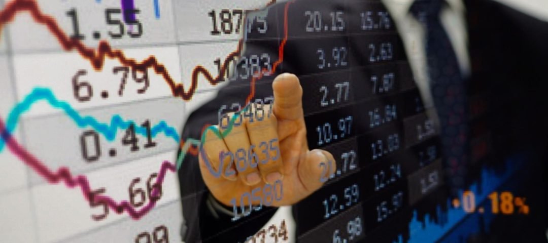 una pantalla con datos de inversiones y una mano señalando