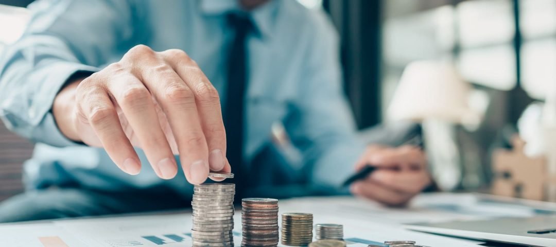 un hombre haciendo montones de monedas sobre una mesa con papeles