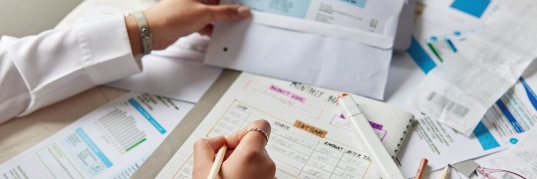 Unas manos comprobando facturas y haciendo cuentas para calcular el ratio de endeudamiento
